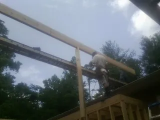 Carpenter setting a ridge beam over a new addition frame — Ice Dam Removal by Roofing Brothers in New Lothrop