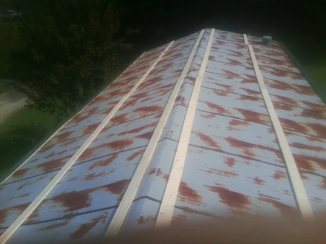 Rusted metal roof panels with new wood purlins before replacement — Storm Damage Roof Repair in New Lothrop by Roofing Brothers