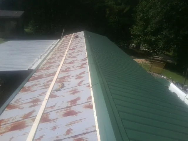 Old rusted panels beside newly installed green metal roofing — Wind Damage Roof Repair by Roofing Brothers in New Lothrop
