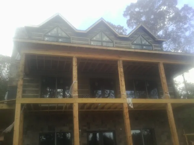 Dormers and porch framing on a large log home under construction — Roof Coating work by our crew in New Lothrop