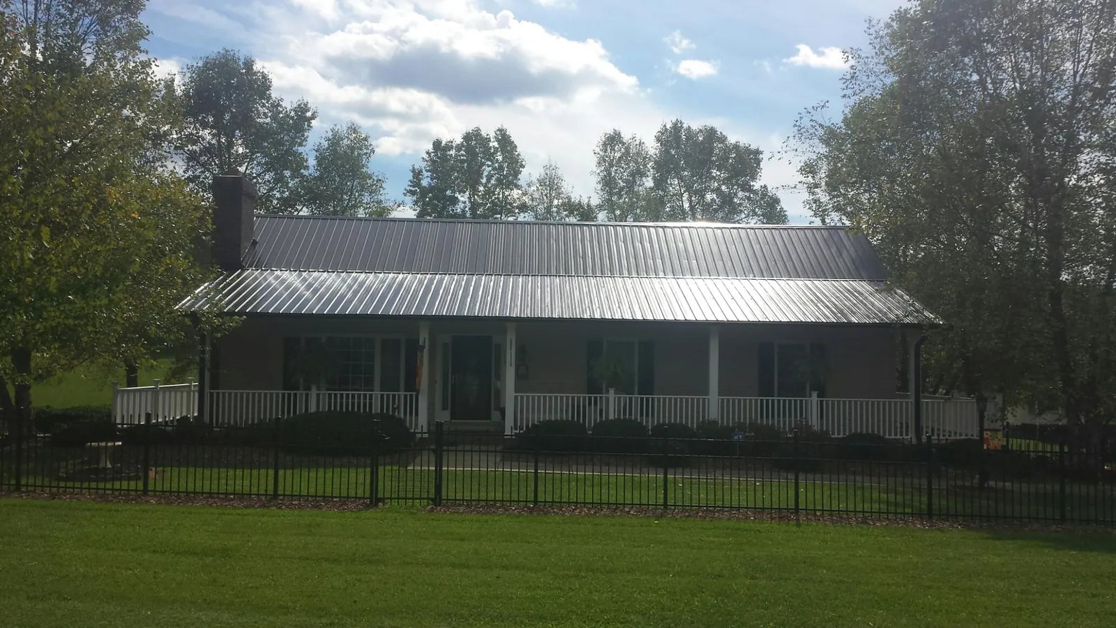 Gray metal roof on a brick ranch with a full width front porch — Gutter Guard Installation work by our crew in New Lothrop