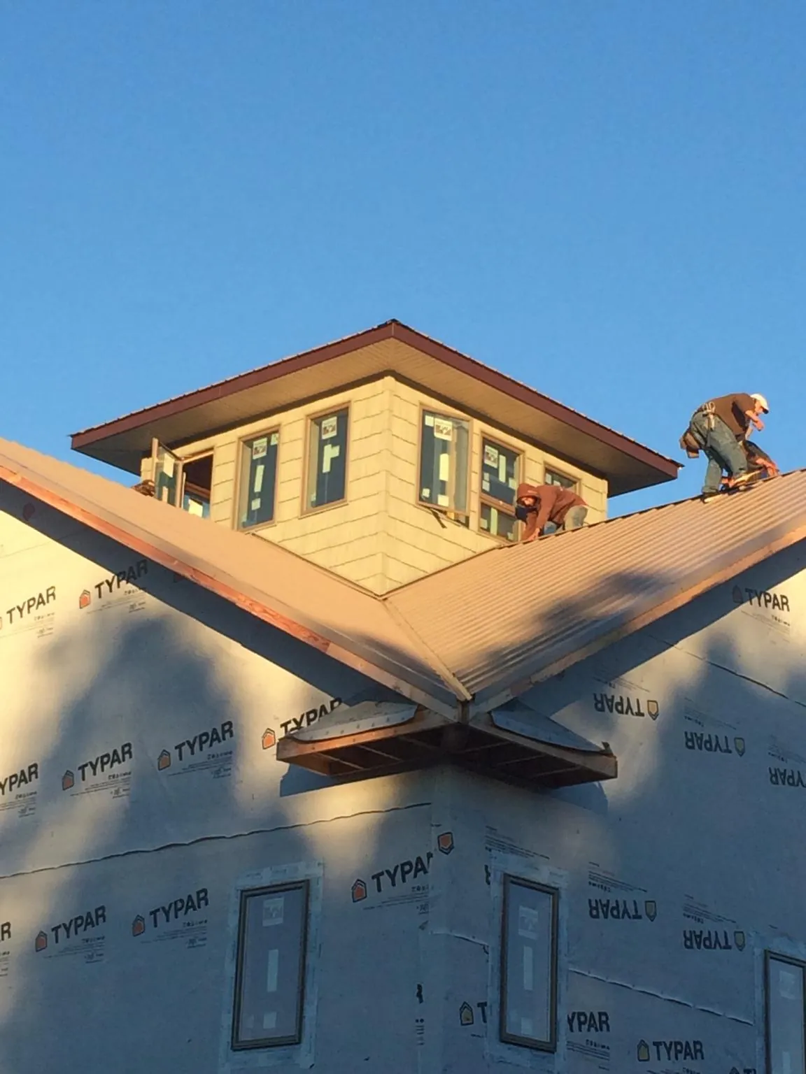Roofers working around a rooftop cupola on a new metal roof at sunset — Roof Waterproofing in New Lothrop by Roofing Brothers